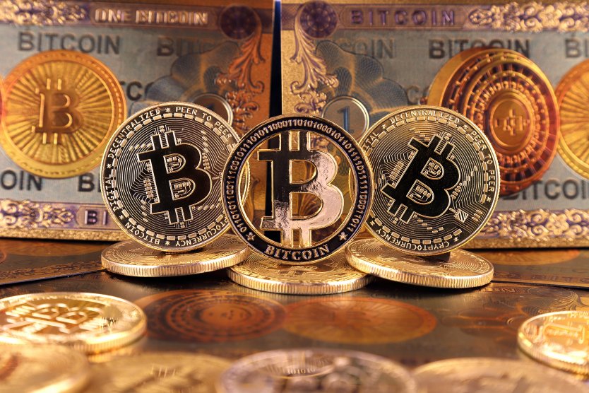 Physical bitcoins pictured in front of a backdrop of notes