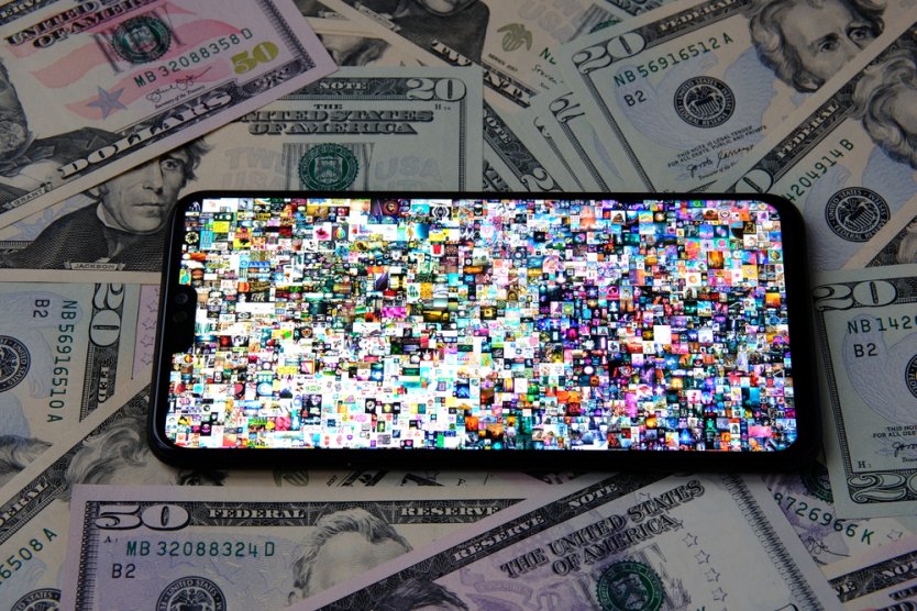 A smartphone, resting on dollar bills, displays Beeple’s NFT, Everydays: the first 5,000 days 