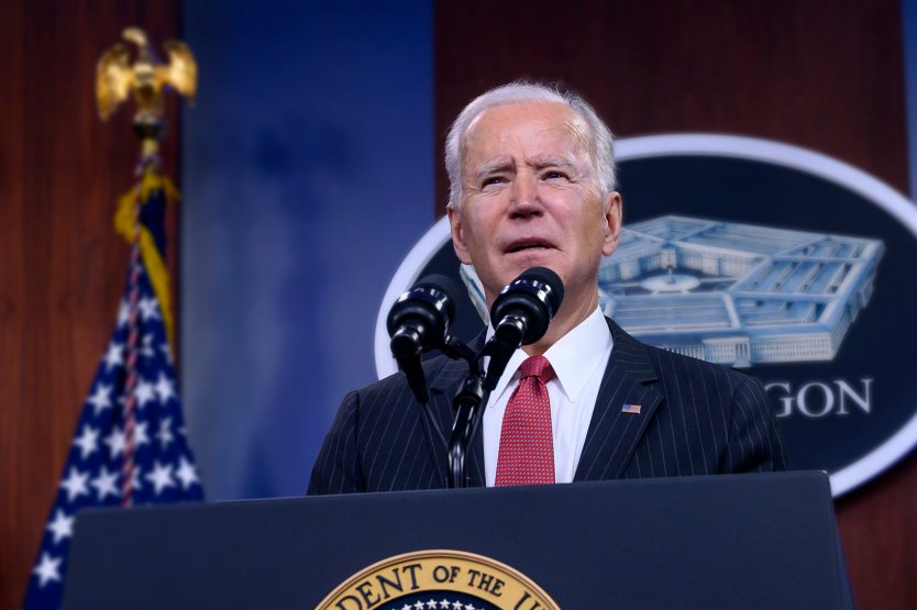 US President Joe Biden speaks into a microphone at a lectern in front of the Pentagon's sign