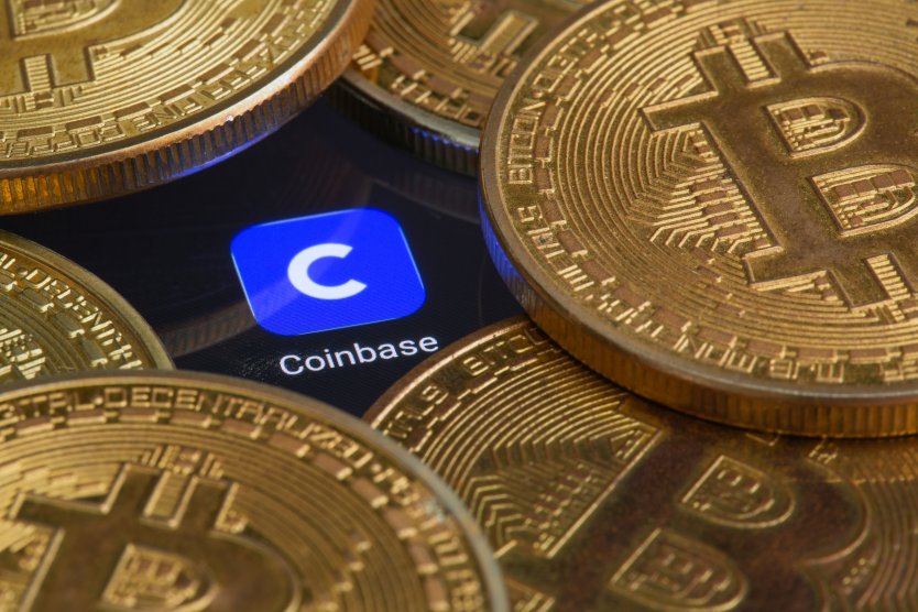 Crypto coins rest on top of a smartphone displaying the Coinbase logo