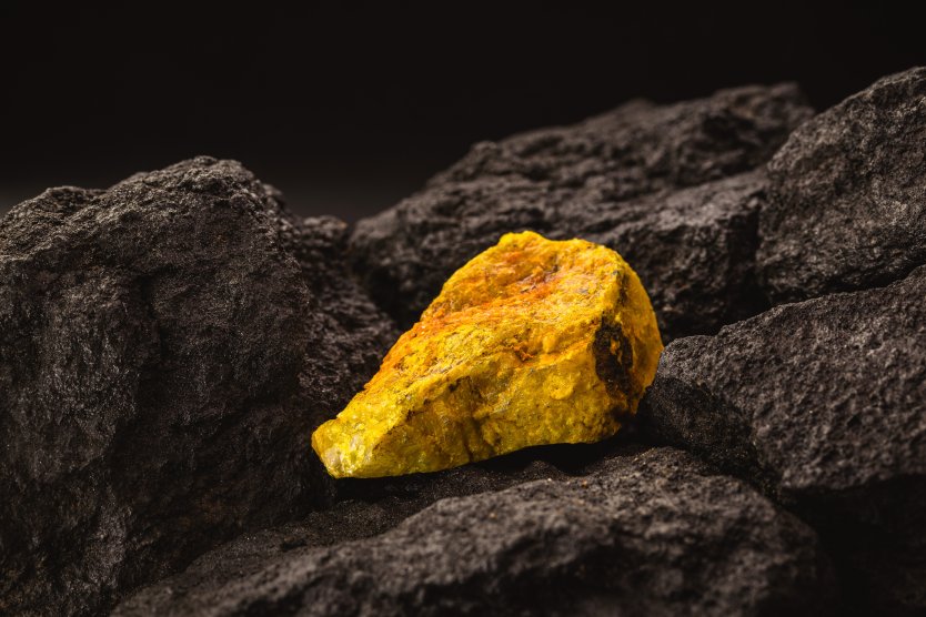 A yellow glowing shard of ore rests on top of other black rocks