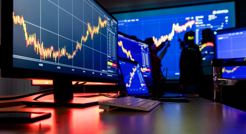 Analysts examine market charts on a wallscreen