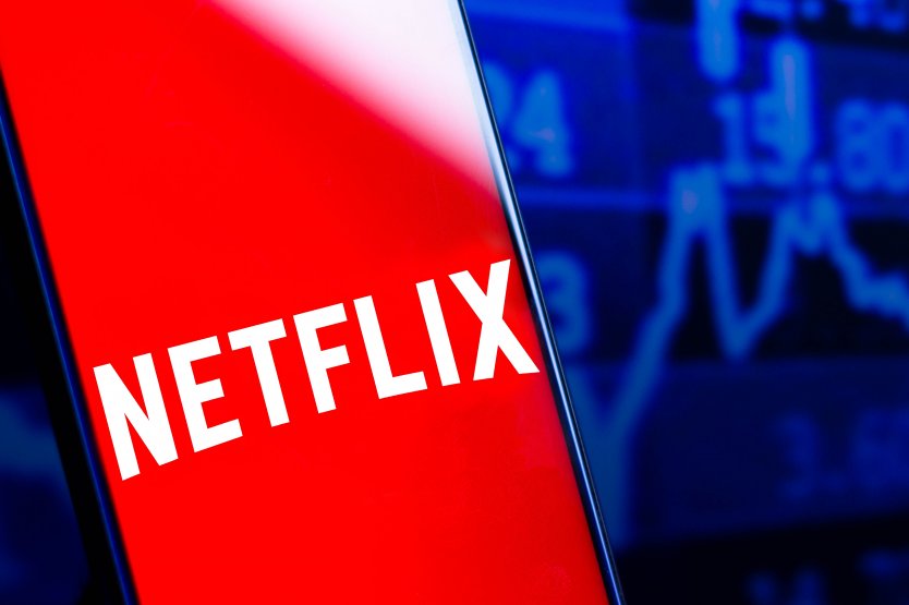 Red Netflix logo shown on a smartphone set against stock prices