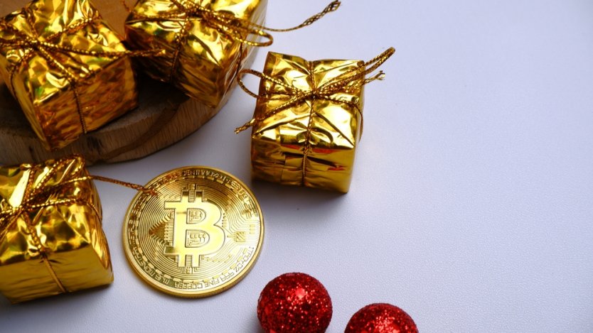 Representation of a bitcoin next to golden Christmas presents and festive decorations