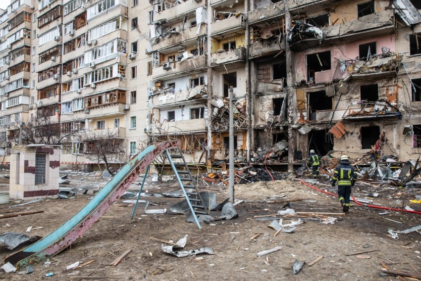 KYIV, UKRAINE - Feb. 25, 2022: A residential building damaged by enemy action in the Ukrainian capital Kyiv, with firefighters at the scene