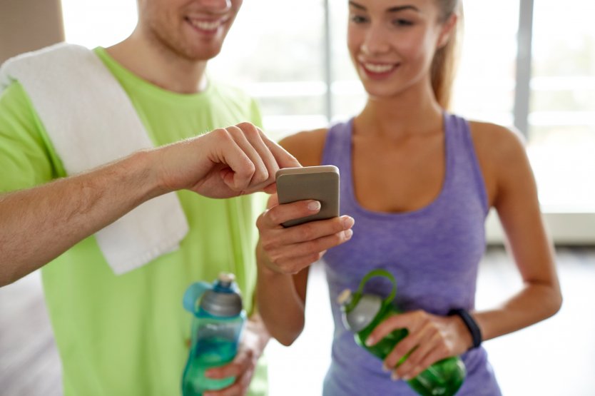 Man and woman working out, looking at phone