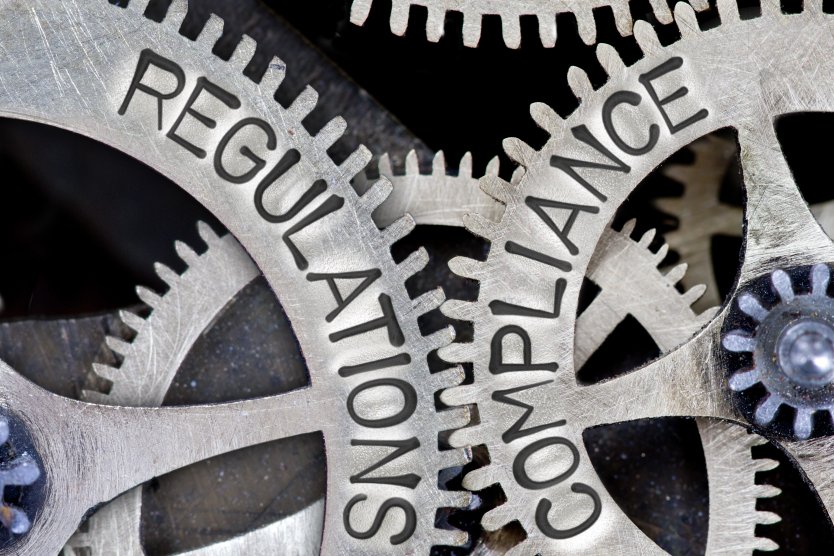 Gear wheels with the words “regulation” and “compliance” written on them – Photo: Shutterstock