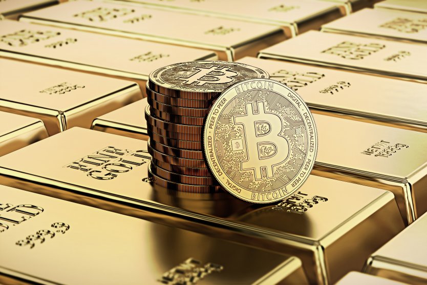 A stack of bitcoins resting on several bars of gold