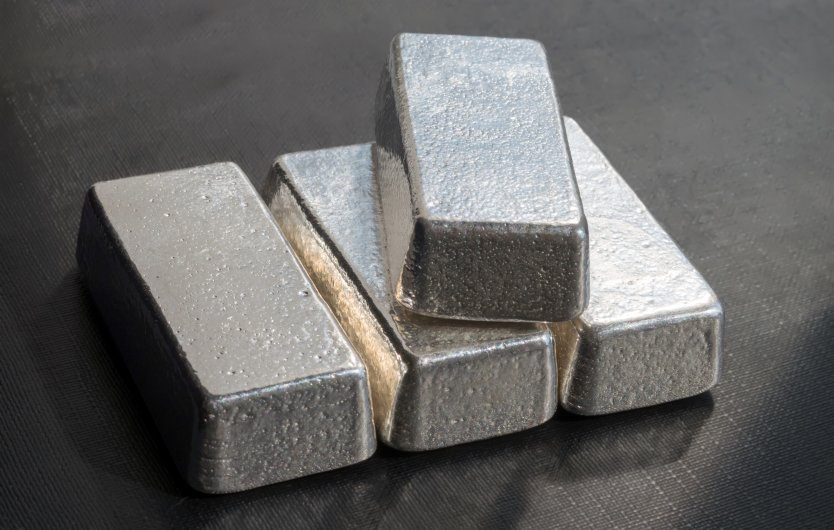 A silver bar lies across three more ingots on a tabletop 